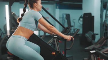 Modern bir spor salonunda kardiyo antrenmanı sırasında spor kıyafetleri içinde staj yapan sağlıklı bir kadın.