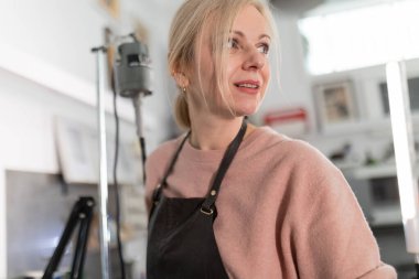 Önlük giyen kadın yaratıcı çalışma alanından ilham almış gibi görünüyor.