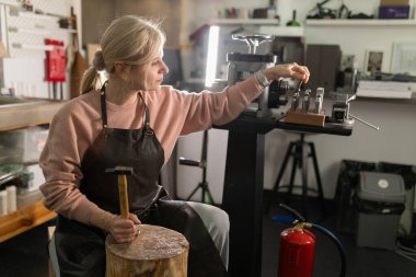 Profesyonel bir stüdyoda aletleriyle metali şekillendirmeye odaklanan bir zanaatkar kadın.