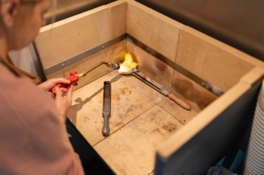 Mücevherci, değerli metali el yapımı için bir potada eritmek için meşale kullanıyor.