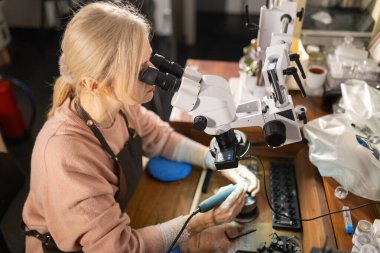 Mikroskop ve özel aletlerle karmaşık detaylar üzerinde çalışan kadın sanatçı
