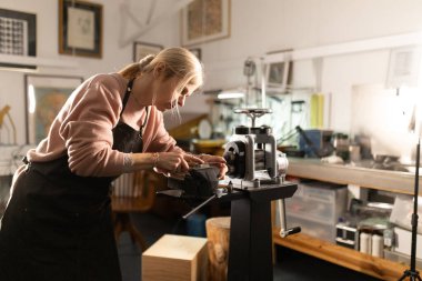 Profesyonel bir atölyede el yapımı parçalar yapmak için metalle çalışan bir zanaatkar.