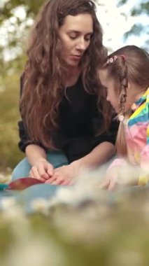 Anne ve kızı bir papatya çayırında hassas bir anı paylaşıyorlar.