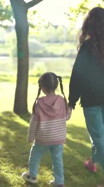 Anne ve kızı yeşil bir parkta huzurlu bir yürüyüş yapıyorlar.