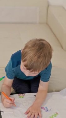 Çocuk renkli kalemlerle kağıda mutlu bir şekilde resim çiziyor, evde yaratıcı oyun zamanlarının keyfini çıkarıyor.