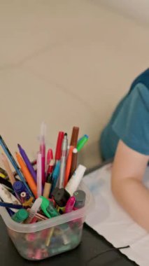 Anaokulu çocuğu evde renkli kalemlerle resim çiziyor.