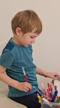 Kreş araştırmacısı yaratıcılığı keşfediyor, beyaz kağıda çeşitli işaretlerle renkli resimler çiziyor.