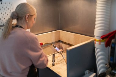 Metal eritme işlemi yapan bir kadın meşale ve mücevher yapımında kullanılıyor.