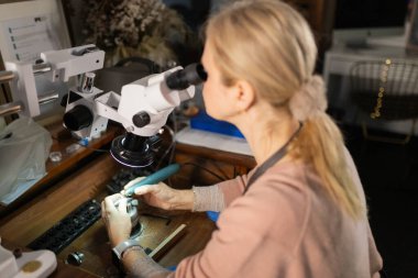 Yetenekli bir zanaatkar mikroskop ve özel aletler kullanarak karmaşık mücevherler yapıyor.