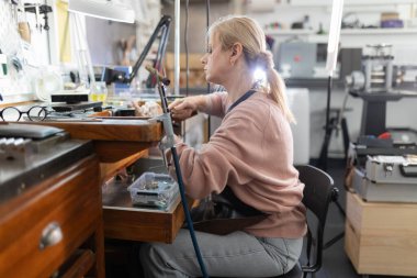 Özel bir tezgahta el yapımı mücevherler üzerinde çalışan kadın bir zanaatkar.