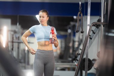 Spor giyim ve içme suyu ayarlayan bir kadın, beden eğitimi eğitimine ara veriyor.