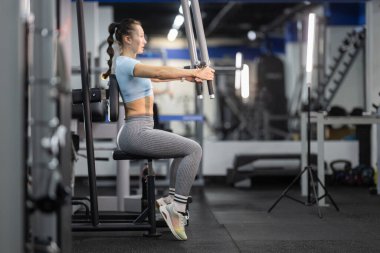 Göğüs presi egzersizi yapan bir kadın, spor salonunda dayanıklılık ve zindelik arttırıyor.