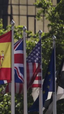 Modern bir binanın önünde çeşitli ulusal bayraklar sallanıyor.