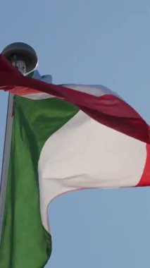 Açık mavi gökyüzüne karşı bayrak direğinde sallanan İtalyan bayrağı
