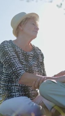 Yaşlı bir çift parkta pikniğin tadını çıkarıyor, el ele tutuşuyor ve konuşuyor.