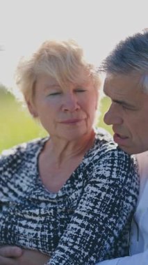 Güneşli bir arazide sevgi gösteren yaşlı bir çift.