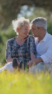 Yaşlı çift doğada romantik bir anın tadını çıkarıyor, çimenlerde bir battaniyenin üzerinde oturuyorlar.