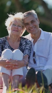 Yaşlı bir çift parkta pikniğin tadını çıkarıyor, birlikte hassas bir anı paylaşıyorlar.