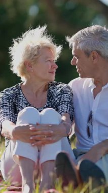 Yaşlı çift güneşli bir parkta romantik bir piknik yapıyor.