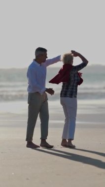 Son sınıf çifti, gün batımında güzel bir sahilde romantik bir dansın tadını çıkarıyor.