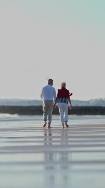 Emekli çift sahilde romantik yürüyüşlerden hoşlanır.