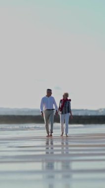 Yaşlı çift sahilde romantik bir yürüyüş yapıyor.