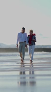 Yaşlı çift sahilde romantik bir yürüyüş yapıyor.