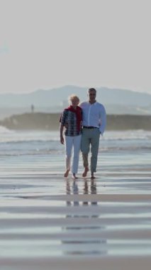 Emekli çift sahilde romantik bir yürüyüş yapıyor.