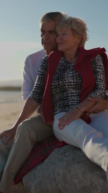 Kıdemli çift gün batımında kumsalda samimi anlar paylaşıyor.