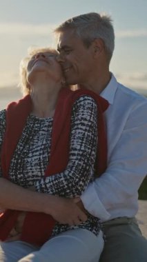 Yaşlı bir çift deniz kenarında romantik bir gün batımının tadını çıkarıyor, kahkahalarını ve sevgilerini paylaşıyorlar.