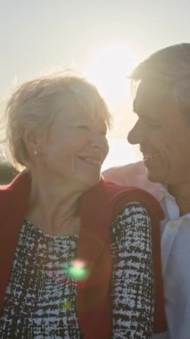 Romantik olgun çift, güzel bir gün batımında kumsalda huzurlu bir anın tadını çıkarıyor.