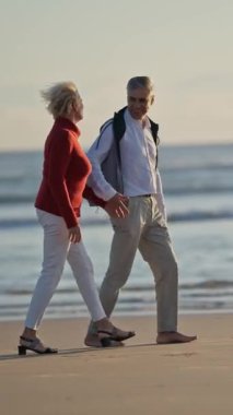 Son sınıf çifti gün batımında sahilde romantik bir yürüyüş yapıyor.