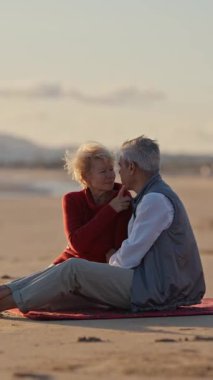 Kıdemli çift gün batımında sahilde romantik bir anın tadını çıkarıyor.