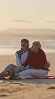 Sevecen son sınıf çifti, altın bir günbatımında sahilde romantik bir anın tadını çıkarıyor.