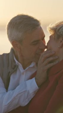 Sevecen son sınıf çifti güzel bir günbatımında sahilde romantik bir anın tadını çıkarıyor.