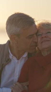 Güzel bir gün batımında kumsalda romantik bir anın tadını çıkaran yaşlı bir çift.