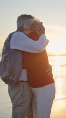 Sevecen yaşlı çift gün batımında sahilde romantik bir anın tadını çıkarıyor.