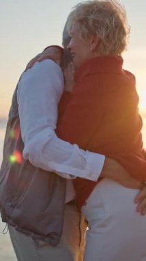 Kıdemli çift gün batımında sahilde romantik bir anın tadını çıkarıyor.