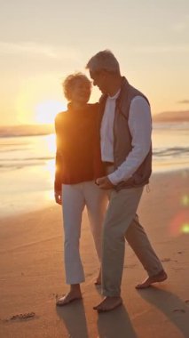 Son sınıf çifti gün batımında sahilde romantik bir yürüyüş yapıyor.