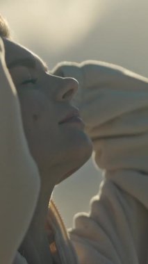 Genç bir kadın, saçlarını güneş ışığında şekillendiriyor.