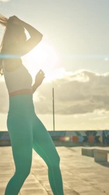 Genç bir kadın gün batımında çatıda antrenman yapmak için hazırlanıyor.