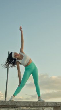 Genç bayan dışarıda esneme egzersizleri yapıyor.