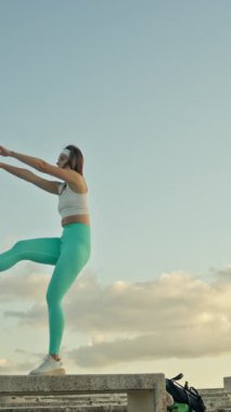 Fitness modeli beton blokta bacak kaldırma egzersizi yapar