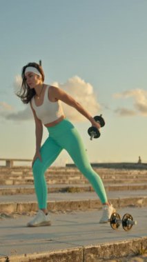 Spor salonundaki kadın dışarıda halterli sıra egzersizi yapıyor.