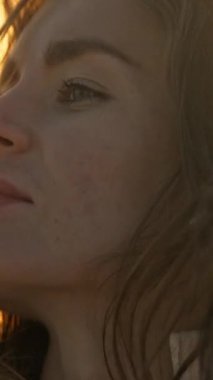 Uzun kahverengi saçlı güzel bir kadının portresi. Altın saat güneş ışığının tadını çıkarıyor.