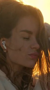 Çekici genç bir kadın kaygısız hissediyor, altın saat güneş ışığının tadını çıkarıyor.