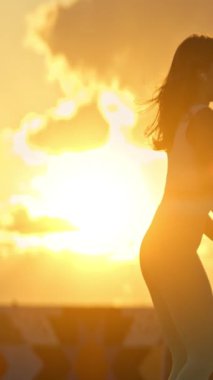 Kadınlar çatıda altın saat boyunca çömelme hareketleri yapıyorlar.