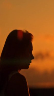 Canlı bir günbatımında zarif hareketler yapan bir bayan atletin silueti.