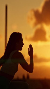 Spor kadını silueti gün batımında koşu pistinde ısınıyor.