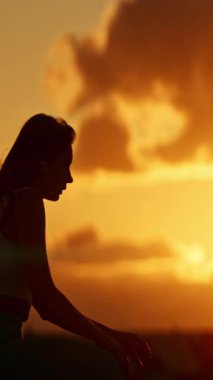 Güzel bir gün batımına karşı ısınan sporcu kadın silueti.